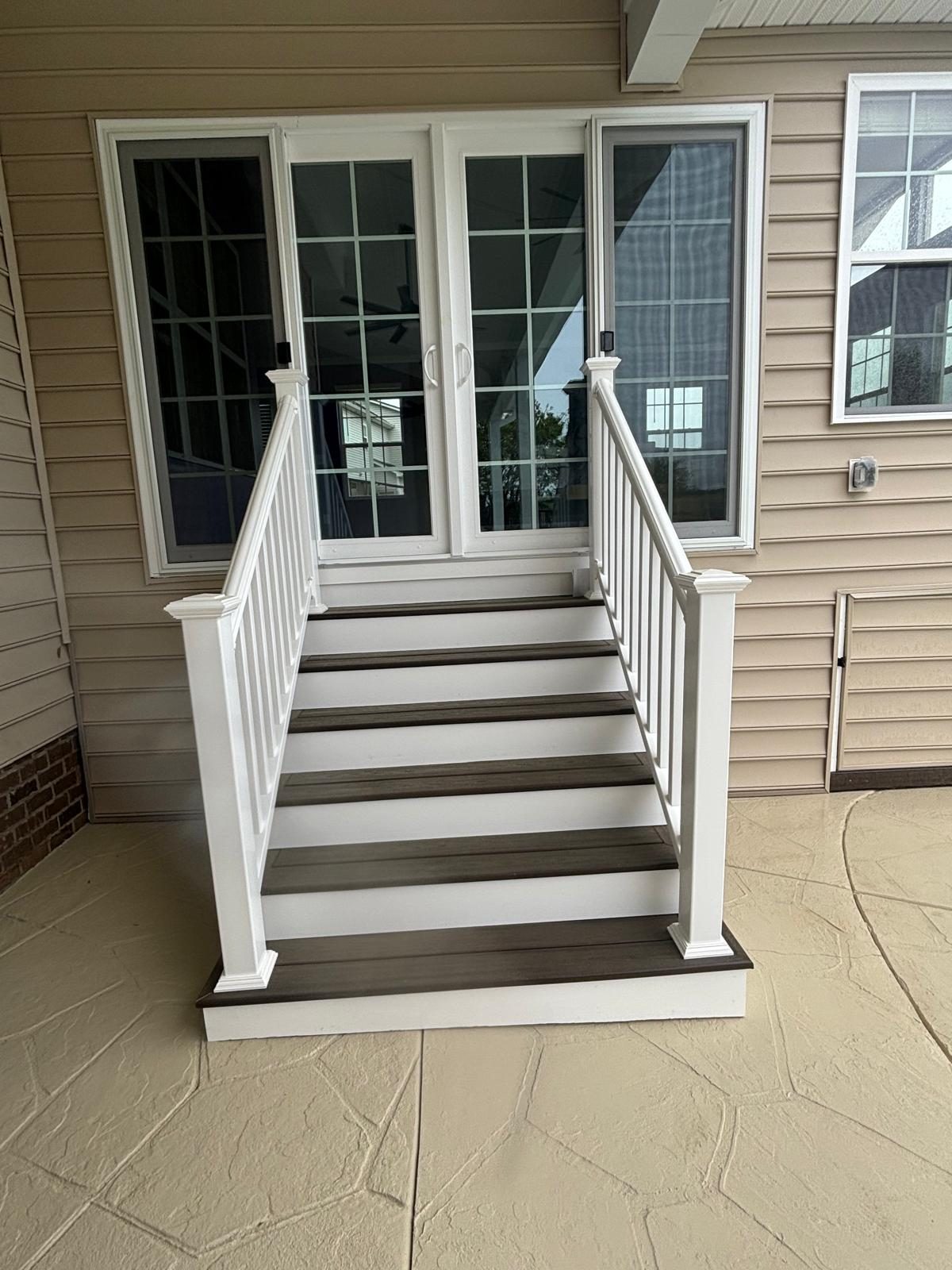 White painted stairs and railing leading from a deck down to a concrete patio