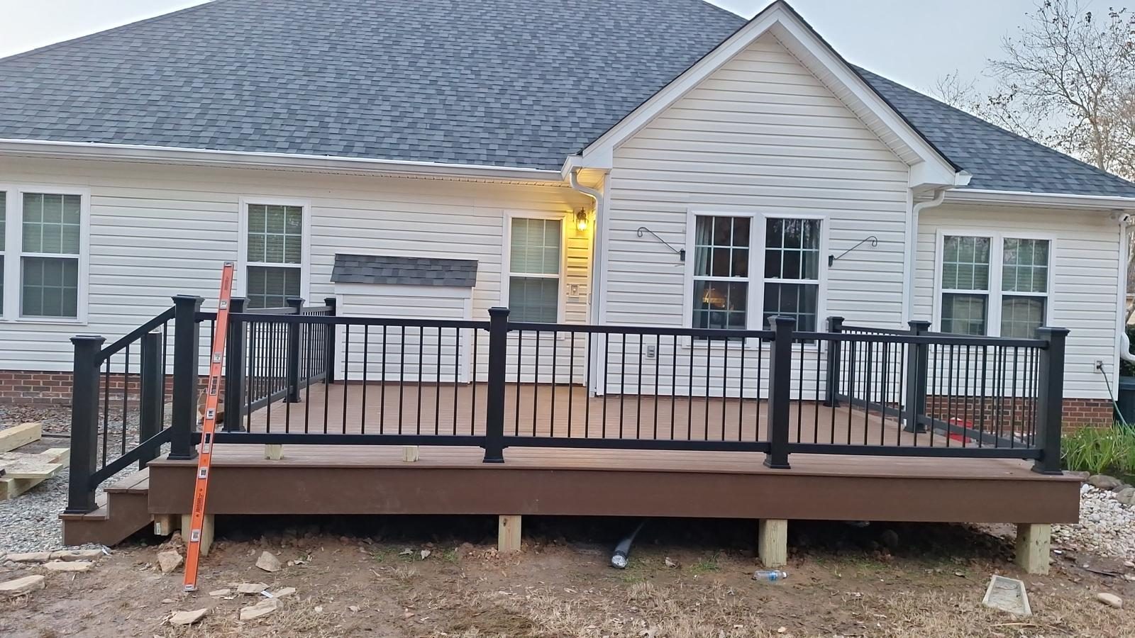 Deck with black metal railings under construction, support posts still exposed