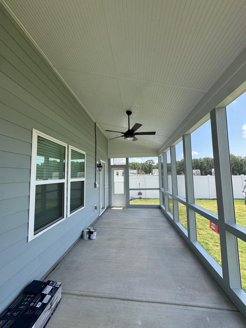 Interior of a finished screened porch with a ceiling fan and windows looking out over the garden