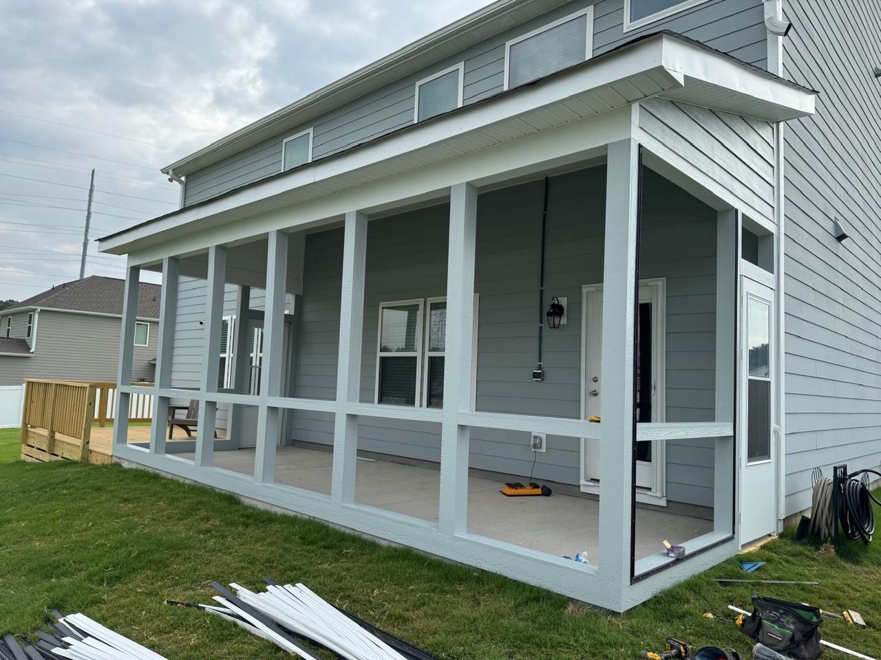 Newly completed screened porch with build materials still stacked on the ground