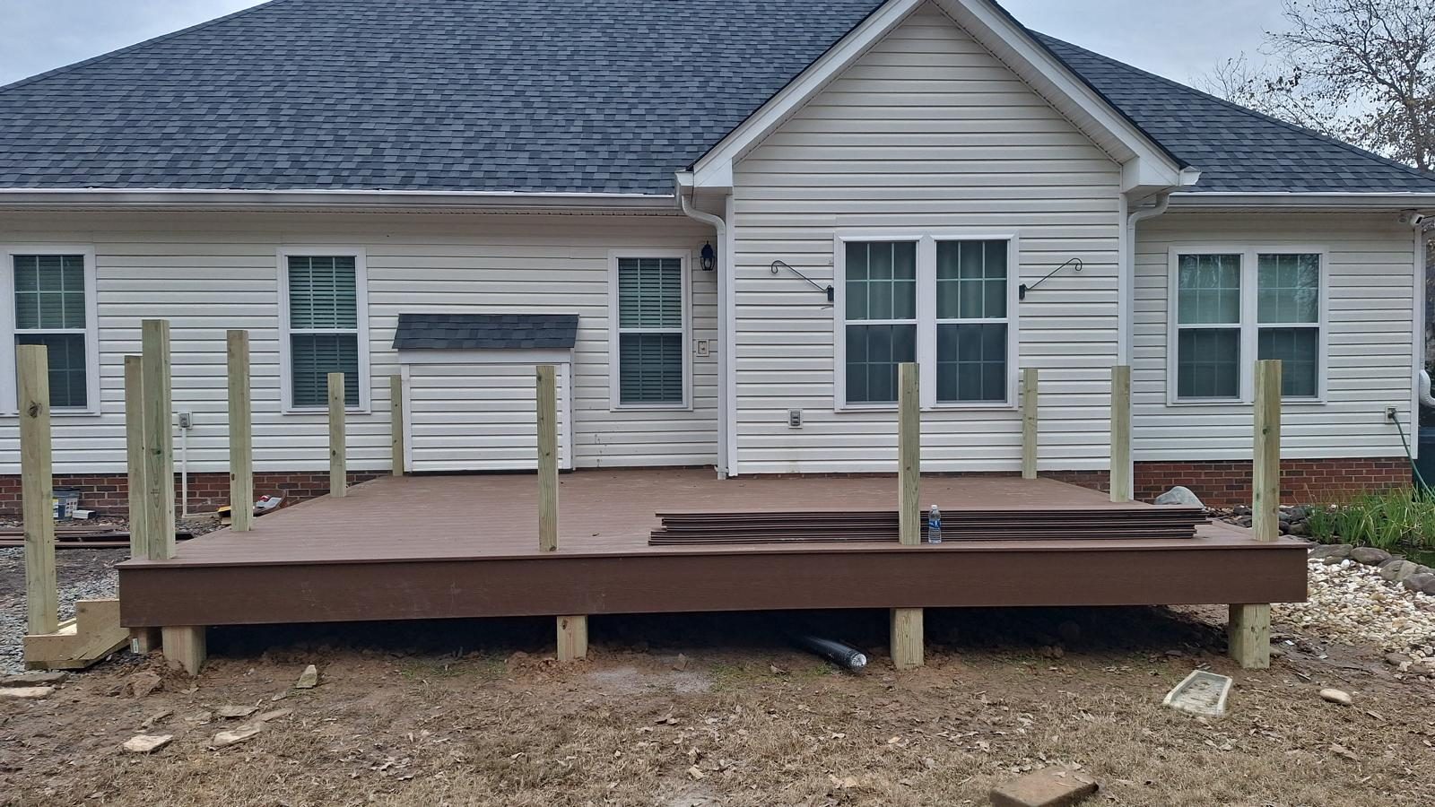 Low composite deck with steps, built along the back of a white house