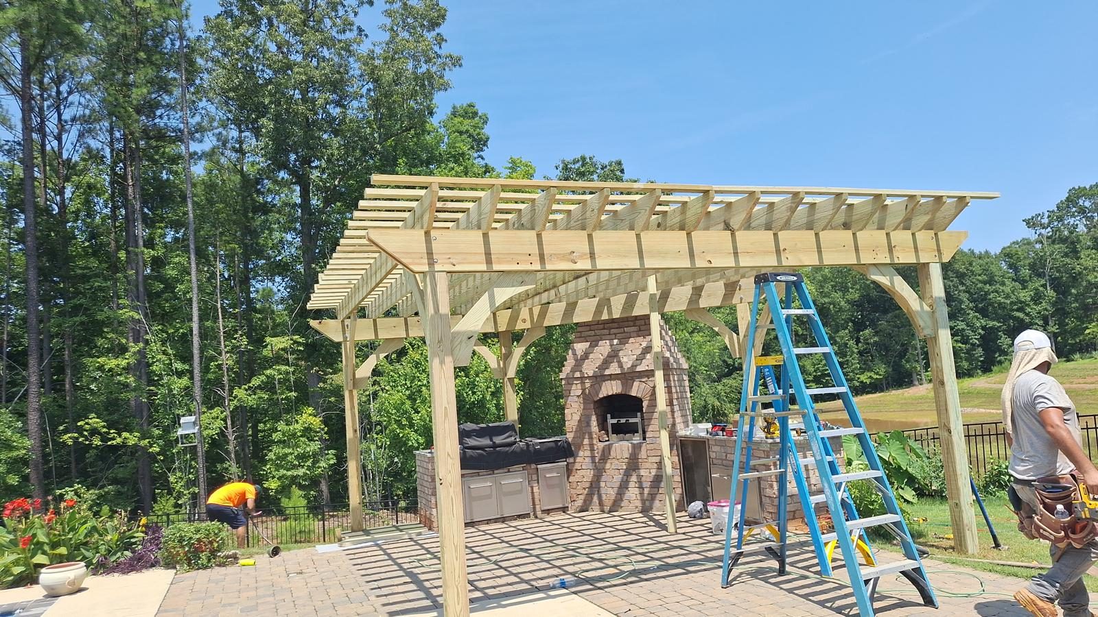 Cedar pergola over a paver patio with a brick outdoor fireplace