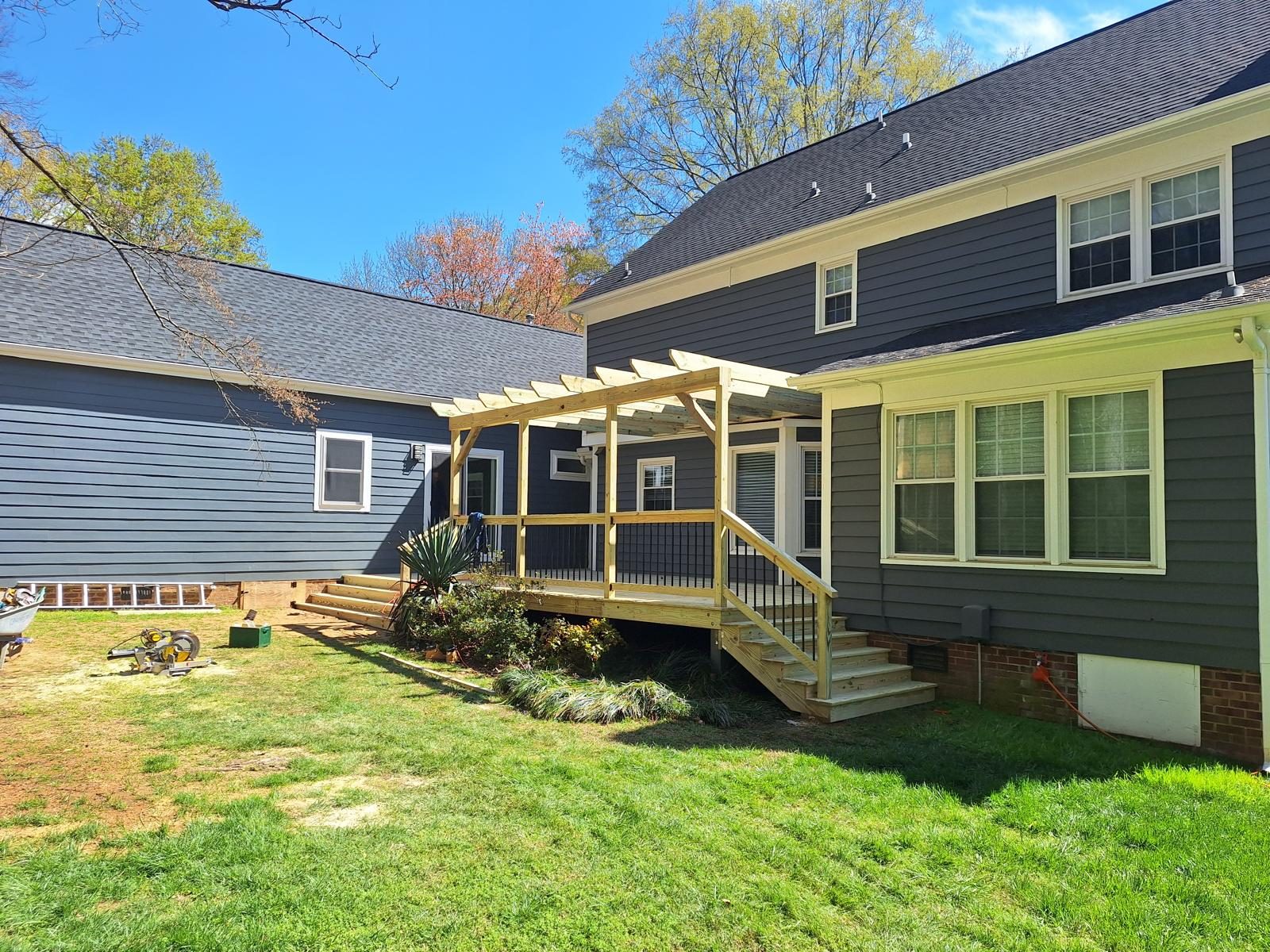 Pergola and deck attached to a green clapboard home