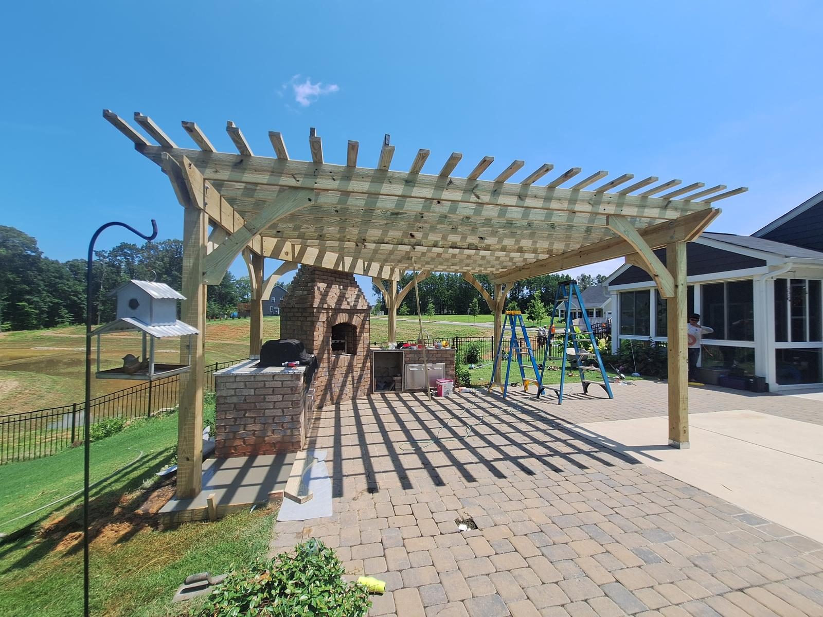 Pergola over a large paver patio beside a planted garden
